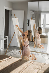 Rear view of mother and daughter sitting on floor