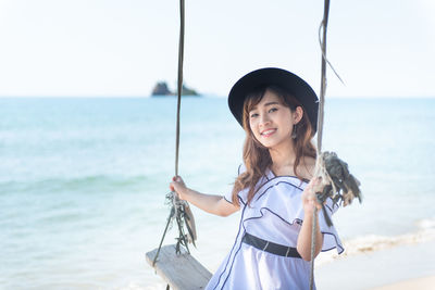 Portrait of smiling woman standing on sea shore against sky