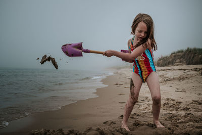 Full length of girl holding umbrella on beach