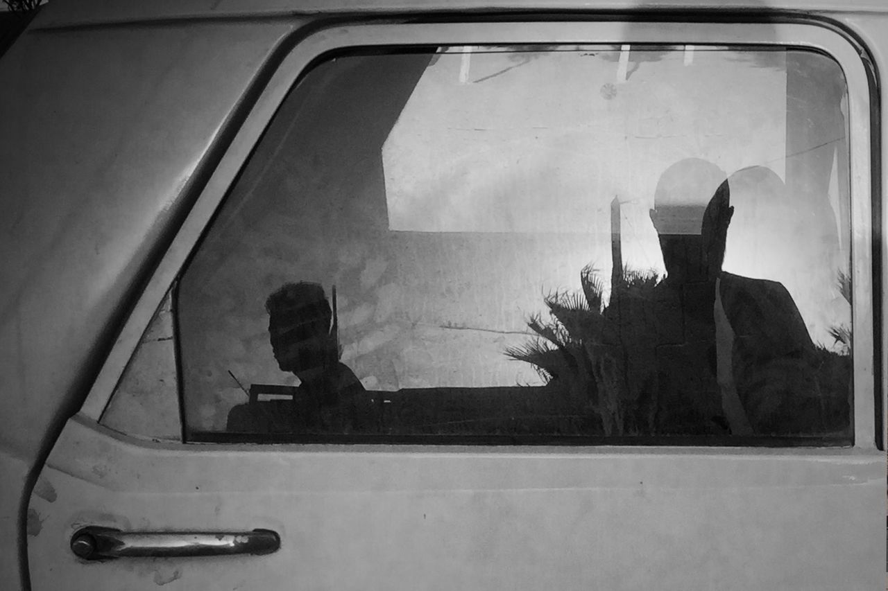 REAR VIEW OF MAN SEEN THROUGH CAR WINDOW