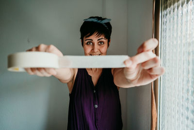 Portrait of young woman standing against wall at home