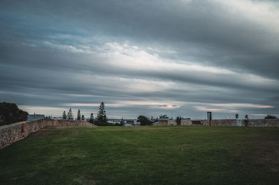 Scenic view of field by buildings against sky