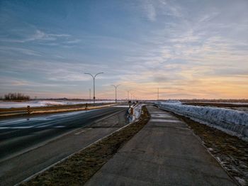 Road by street against sky during sunset