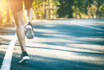 Low section of woman walking on road