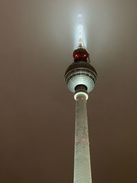 Low angle view of illuminated tower against building at night