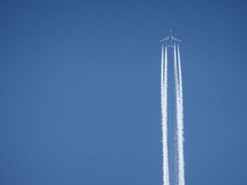 Low angle view of airplane against clear blue sky