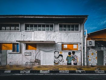People standing by building against blue sky
