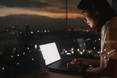 Rear view of woman using laptop at home