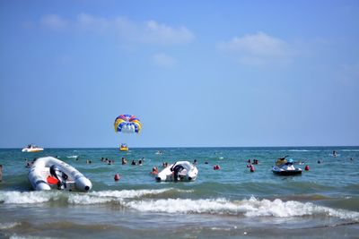 Group of people in calm sea against blue sky