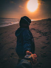 Girl on beach against sky during sunset