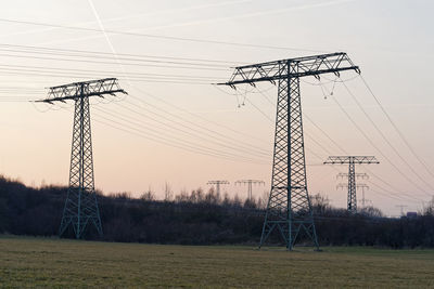 Low angle view of electricity pylon on field against sky