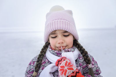 Cute girl licking ice during winter