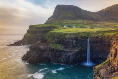 Scenic view of sea by mountains during sunset