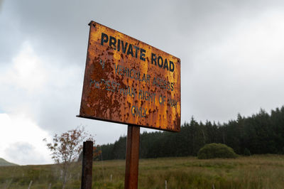 Information sign on field against sky