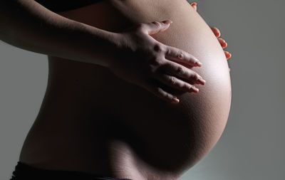 Close-up of woman touching hair over black background