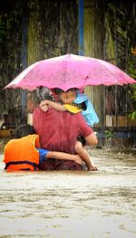 Man holding umbrella while sitting in rain