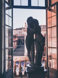 Statue of woman standing against window