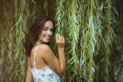 Portrait of smiling young woman touching leaf