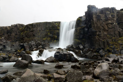 Low angle view of waterfall against clear sky