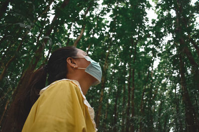 Side view of woman standing against trees