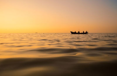 Silhouette people in boat against clear sky during sunset