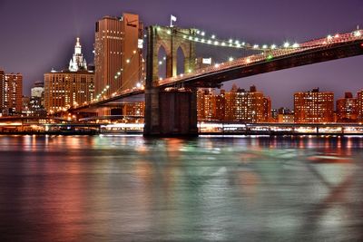 Illuminated brooklyn bridge over east river in city