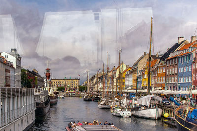 Sailboats in river by buildings in city against sky