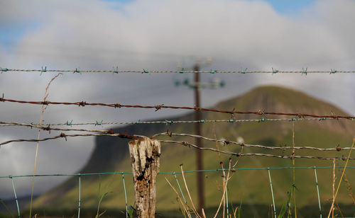 Close-up of barbed wire against sky