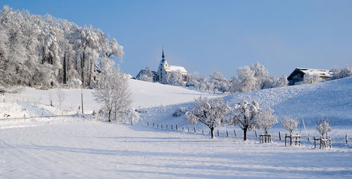 Snow covered landscape against clear blue sky