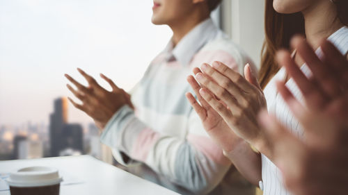 Midsection of business people applauding in office