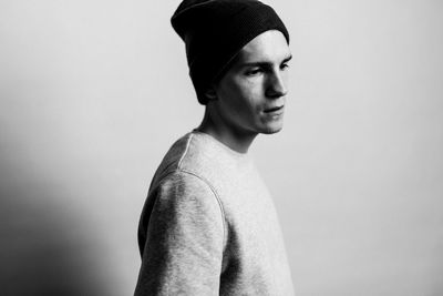 Thoughtful young man standing against white background