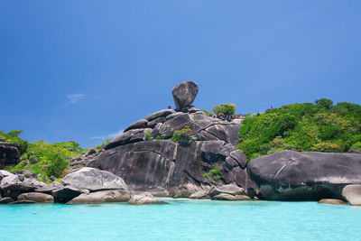 Rock formation in sea against blue sky