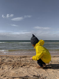 Cute boy crouching on beach