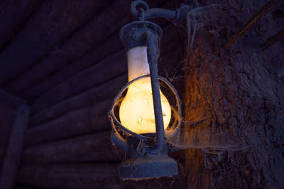 Low angle view of illuminated light bulb hanging on wall