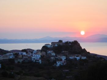 Townscape by sea against sky during sunset