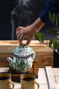 Midsection of person holding tea cup on table