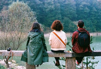 Rear view of friends sitting on wooden railing