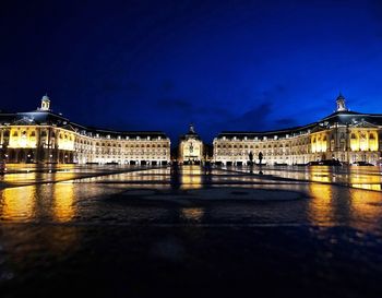 Illuminated building against blue sky at night