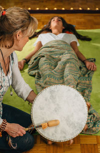 Therapist playing drum by young woman at spa