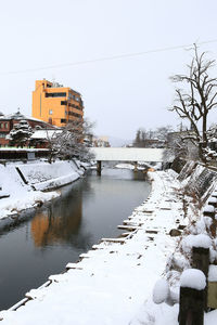 Scenic view of frozen canal by buildings against sky