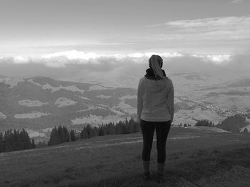 Rear view of woman standing on field against sky during winter