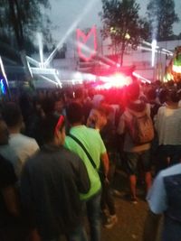 Crowd on illuminated street against sky at night