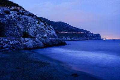 Scenic view of sea and mountains against blue sky