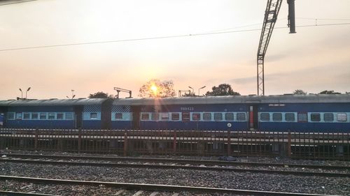 Railroad tracks against sky during sunset