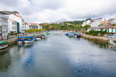 Boats in river by buildings against sky