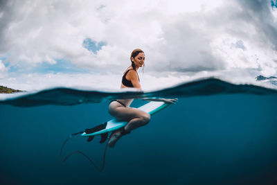 Full length of woman with arms raised against sky