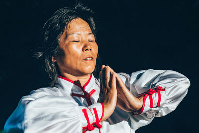 Mature woman practicing martial arts against black background