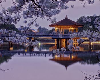 Illuminated building by lake at dusk