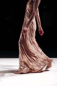 Long beige glittering dress on a female figure, stylish fashion clothing details