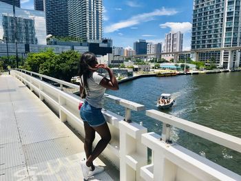 Man standing on railing by buildings in city